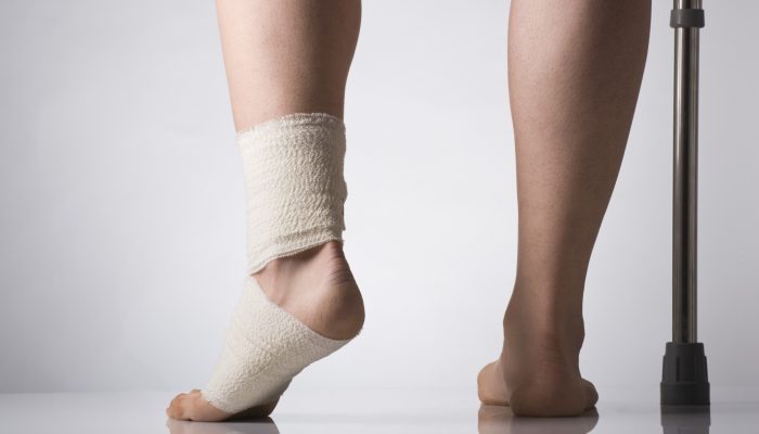 Person wearing support bandage and holding crutch