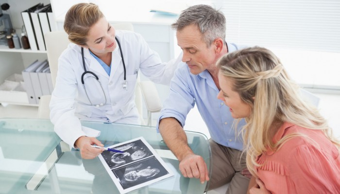 31893444 - happy couple talking to doctor while looking at ultrasound