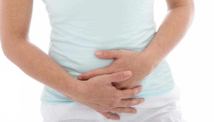 Cropped view of the hands of a woman with stomach pain clutching her stomach, isolated on white