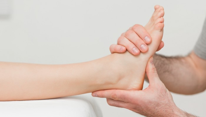 Hands of an osteopath massaging a foot in a room