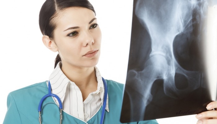 Thoughtful female doctor in the green uniform looking at the x-ray image