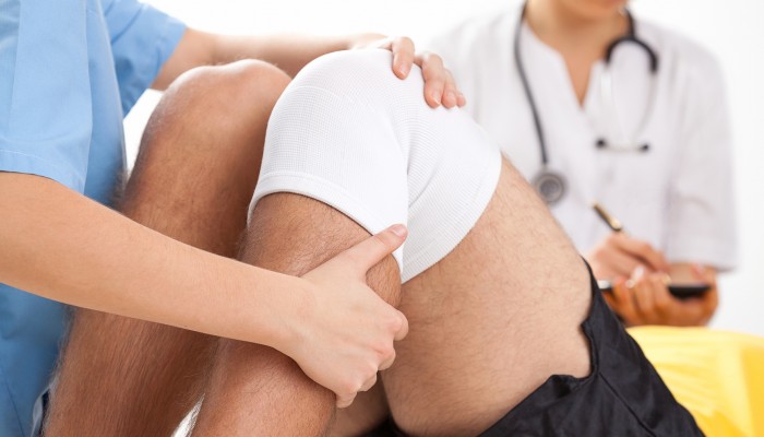 Doctor supervising the recovery of his patient after knee surgery