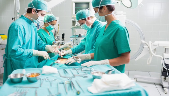 Side view of a surgical team operating a patient in an operation theatre