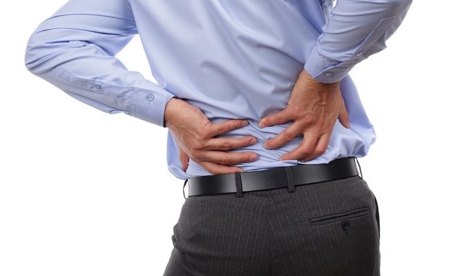 Backache concept bending over in pain with hands holding lower back