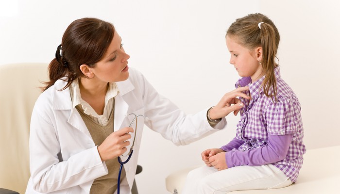 Female doctor examining child holding stetoscope at surgery