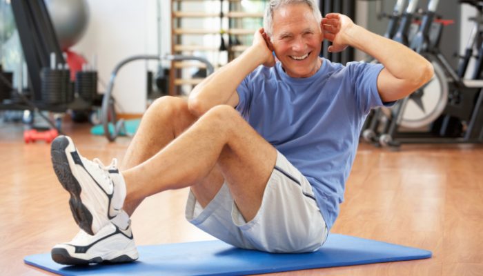 Senior Man Doing Sit Ups In Gym