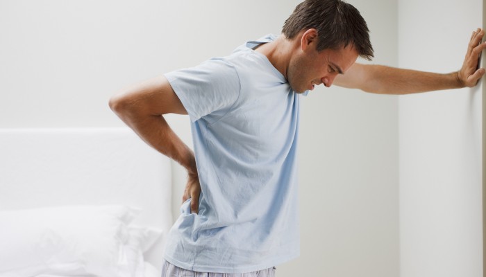 Man with backache leaning against wall