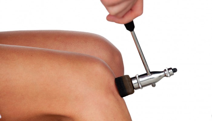 The neurologist testing knee reflex using a hammer