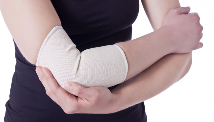 Image of an athlete woman having an elbow pain wrapped with a bandage against the white background